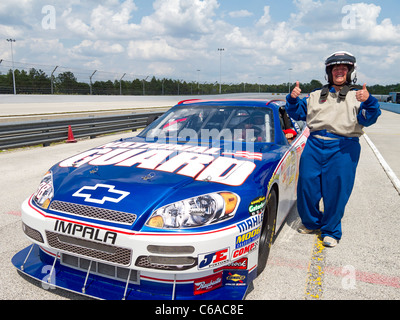 Femme sur le point de monter autour de la piste de course à 150 mph avec race driver en voiture NASCAR à Richard Petty driving school, Disney World Banque D'Images