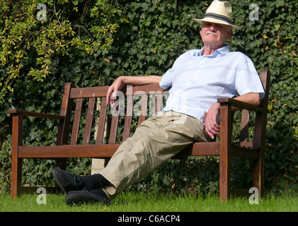 Vieil homme dort sur son banc de jardin Banque D'Images