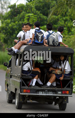 Écoliers en uniforme à l'intérieur et sur le dessus d'une mini-fourgonnette de les prendre à l'école à Bukit Lawang Banque D'Images