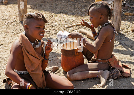 Manger du gruau de maïs filles Himba dans village près d'Opuwo, Namibie Banque D'Images