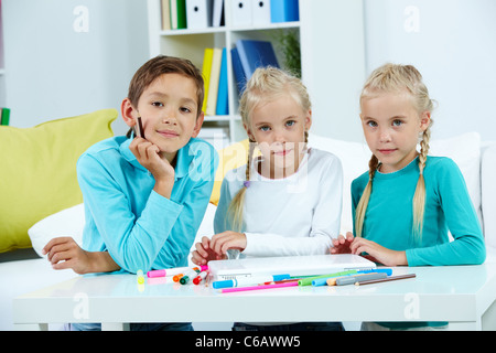 Smart schoolboy et twin girls looking at camera Banque D'Images