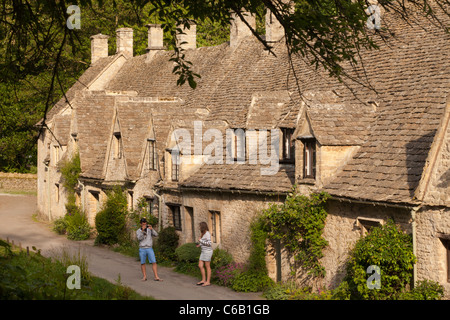 Un jeune couple profitez d'une promenade en soirée à côté d'Arlington Row dans le village de Cotswold, Gloucestershire Bibury Banque D'Images