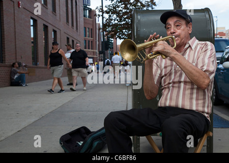 Denver, Colorado - un musicien de rue joue de la trompette pour des conseils en tant que fans arrivent à Coors Field pour un match de baseball. Banque D'Images