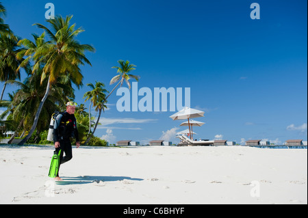 Scuba Diver à pied à partir de la mer plage à l'Alila Villas Hadahaa Resort, North Huvadhoo Atoll, aux Maldives Banque D'Images