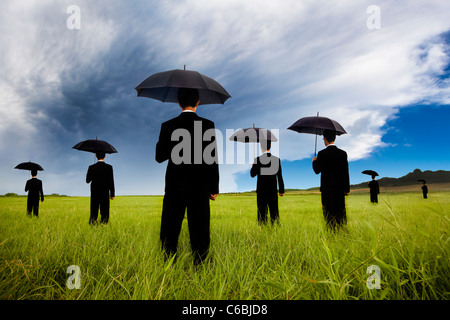 Homme d'affaires en costume noir holding umbrella et regardant le storm coming Banque D'Images