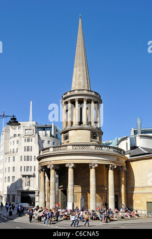 Les gens assis sur les marches de l'église All Souls Langham Place conçu par John Nash BBC Broadcasting House au-delà de Regent Street North London England UK Banque D'Images