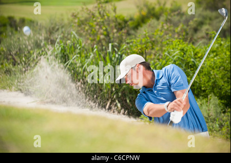 Caucasian golfer hitting ball out de bunker Banque D'Images