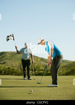 Caucasian golfer putting on golf course Banque D'Images