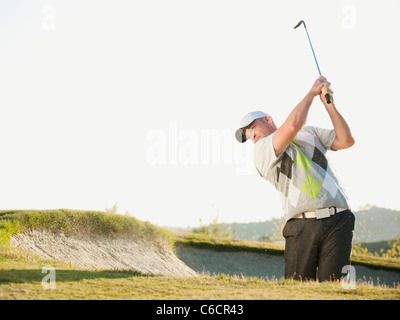 Caucasian golfer hitting ball out de bunker Banque D'Images