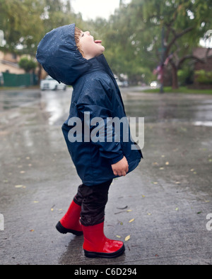 Young boy attraper les gouttes de pluie sur le timon Banque D'Images