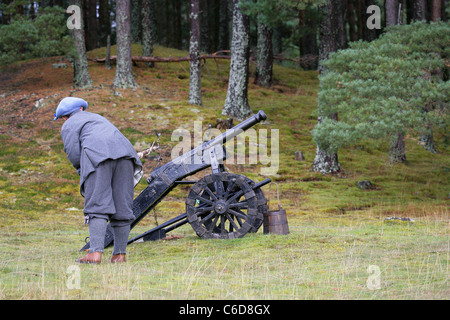 Membre de [Fraser's Dragoons], un 17e siècle re-enactment society, tirant un canon par l'application d'un fusible allumé au trou [touch] Banque D'Images