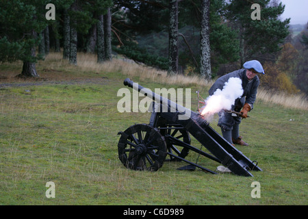 Membre de [Fraser's Dragoons], un dix-septième siècle re-enactment society, le tir d'un canon, montrant des flammes par le trou [touch] Banque D'Images