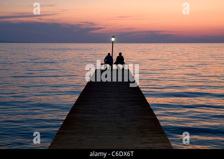 Pêcheurs sur une jetée au coucher du soleil, la Grèce, de Molivos Banque D'Images