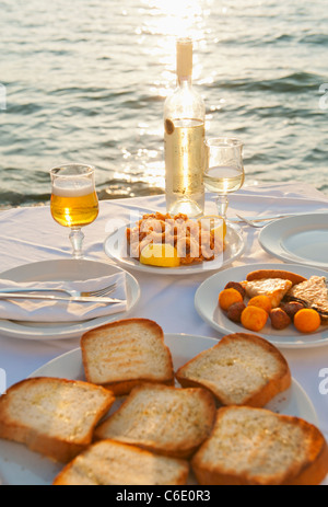 La Grèce, Îles Cyclades, Mykonos, calamars apéritif sur set table par mer Banque D'Images