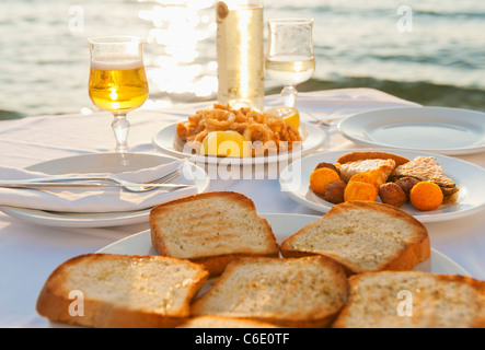 La Grèce, Îles Cyclades, Mykonos, calamars apéritif sur set table par mer Banque D'Images