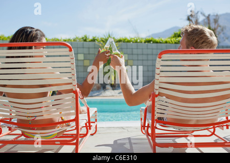 Couple toasting with beer at poolside Banque D'Images