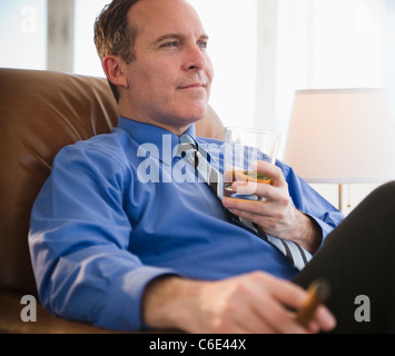 USA, New Jersey, Jersey City, Businessman relaxing avec boisson et de cigare Banque D'Images