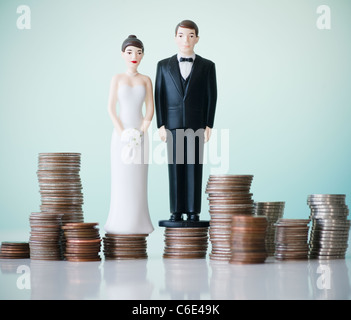 Close up of wedding cake figurines sur des piles de pièces de monnaie Banque D'Images