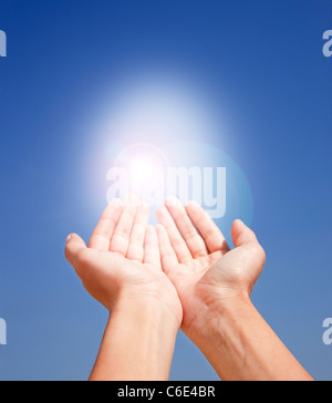 USA, New Jersey, Jersey City, Close up of woman's hands holding la lumière du soleil sur le ciel bleu Banque D'Images