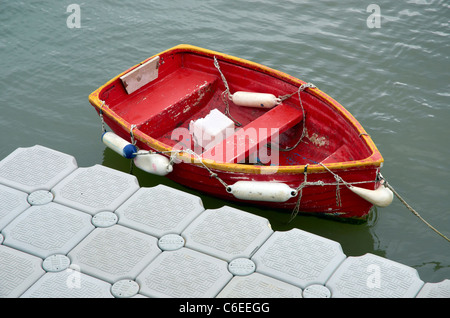 Petit bateau à rames rouge ou canot le long d'un ponton en plastique à la fin de la Cobb à Lyme Regis, dans le Dorset, Angleterre Banque D'Images