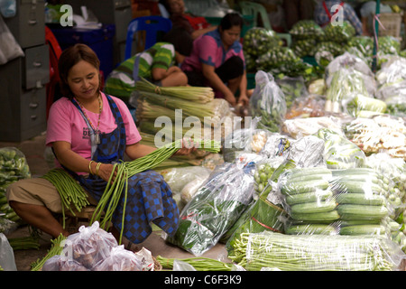 Une femme prépare des légumes pour la vente dans le marché de vente en gros de fruits et légumes à Bangkok Banque D'Images