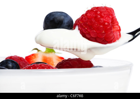 De framboise et de myrtille sur une cuillère avec du yogourt en face d'un dessert sur fond blanc Banque D'Images