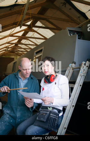 Un mari et sa femme à plus de quelques formalités administratives pour leur entreprise, sur une échelle à l'avant de bateau étroit dans leur entrepôt. Banque D'Images