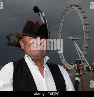 Un homme joue de la cornemuse sur le pont de Westminster, le London Eye est visible en arrière-plan. Banque D'Images