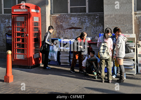 Scène de rue de la ville de Chine les gens se aident à libérer les Chinois Journal dans Chinatown Gerrard Street Londres Angleterre Royaume-Uni Banque D'Images