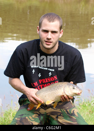 Jeune homme avec une carpe qu'il a capturé, Devon, UK Banque D'Images