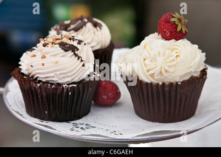 Trois petits gâteaux au chocolat artisanale exquise avec garniture de crème fouettée au chocolat arrosé les écrous et une délicieuse fraise Edmonds Banque D'Images