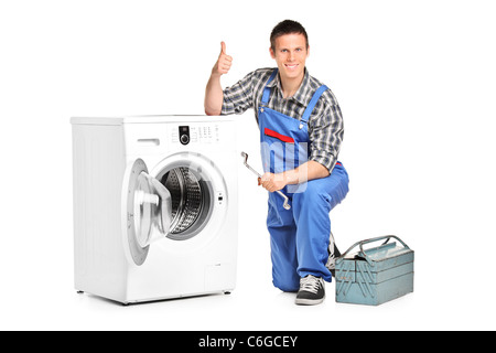 Réparateur d'une holding d'une clé et giving thumb up à côté d'un lave-linge Banque D'Images