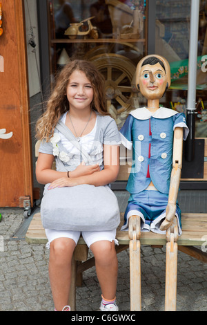 Jeune fille assise sur un banc d'une pleine taille de la marionnette Pinocchio Banque D'Images