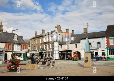 Les gens assis dans la ville pavée carré avec l'horloge publique ornés et pompe à eau. M. Downham Market, Norfolk, Angleterre, Royaume-Uni, Grande Bretagne Banque D'Images