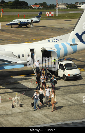 Un Dash-8 G-ECOH désactiver chargement de passagers à l'aéroport de Guernesey avec un Blue Islands G-BAe Jetstream 31 ISLB 3202 dans l'arrière-plan. Banque D'Images
