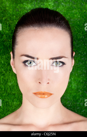 Closeup portrait d'une belle femme en colère graves avec des yeux verts et des lèvres brillant sur fond vert Banque D'Images