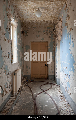 Couloir menant à une vieille porte dans l'asile psychiatrique d'un hôpital à l'abandon de l'aile Banque D'Images