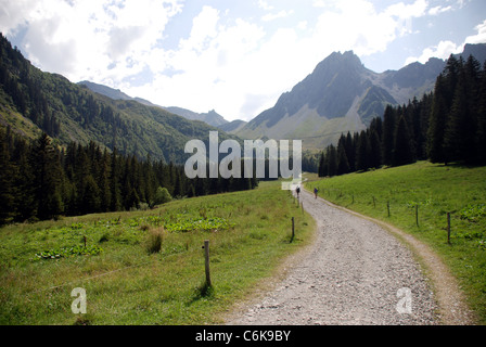 Une route de montagne traverse une vallée dans les Alpes françaises avec de hautes montagnes en arrière-plan Banque D'Images