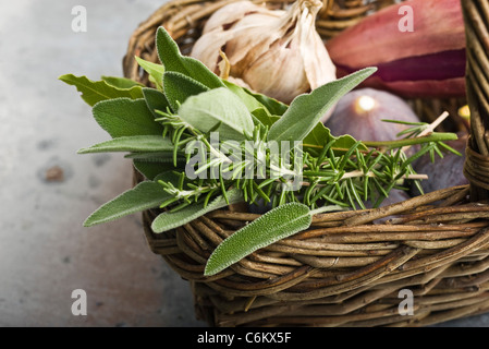 Des herbes fraîches dans panier avec de l'ail, les échalotes, et des figues Banque D'Images