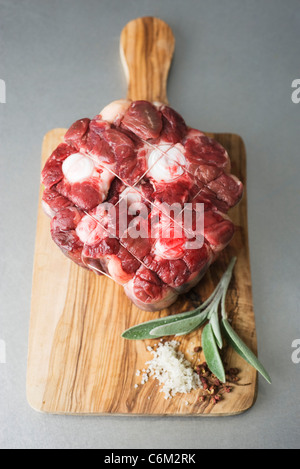 Matières premières fraîches bovine, sage et gros sel on cutting board Banque D'Images