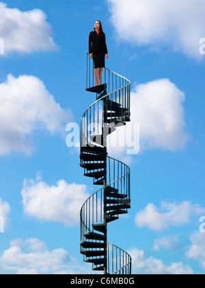 Femme debout en haut d'escalier métallique passant par ciel bleu avec des nuages blancs gonflés Banque D'Images