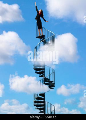 Une femme ayant atteint vers le haut du châssis l'article en haut de l'escalier en spirale qui s'élève à travers ciel clair avec puffy white clouds Banque D'Images