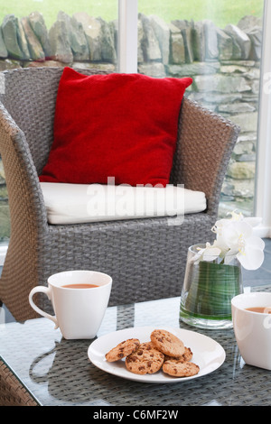 Café et biscuits dans un style moderne mais confortable home intérieur avec mobilier en rotin dans une véranda salon Banque D'Images