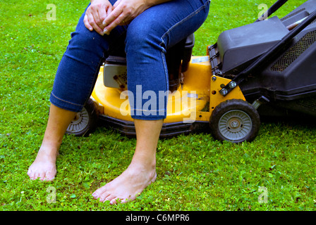 Femme prend une pause à partir de travaux de jardinage, assis sur une tondeuse Banque D'Images