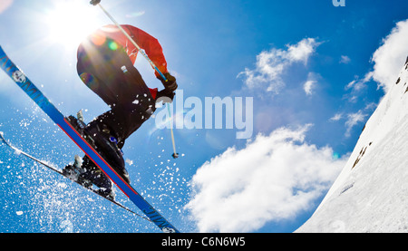 Skieur dans l'air de sauter devant le soleil contre le fond de ciel bleu Banque D'Images