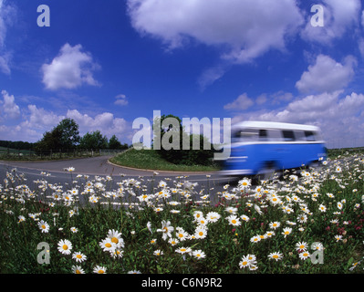 Low angle view of volkswagen camper van voyageant le long de routes de campagne, en passant les fleurs sauvages Yorkshire UK Banque D'Images