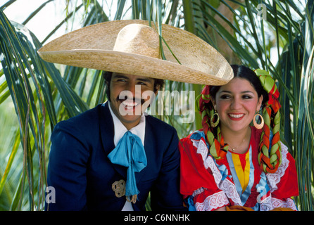 Un couple de danse folklorique traditionnelle mexicaine dans leurs costumes colorés se détendre à l'ombre de palmiers entre représentations à Puerto Vallarta, au Mexique. Banque D'Images