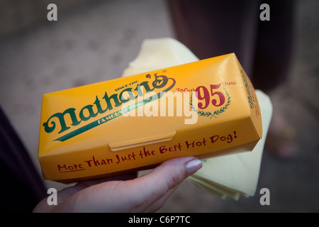 Un client est titulaire d'un hot-dog à l'original du célèbre restaurant Nathan se dresse sur Coney Island dans quartier de Brooklyn à New York Banque D'Images