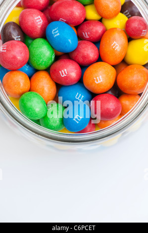 M & M s dans un bocal en verre sur fond blanc doux Banque D'Images