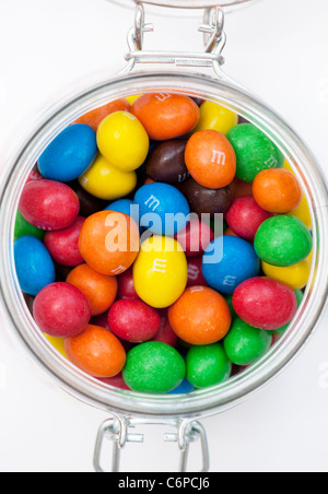 M & M s dans un bocal en verre sur fond blanc doux Banque D'Images